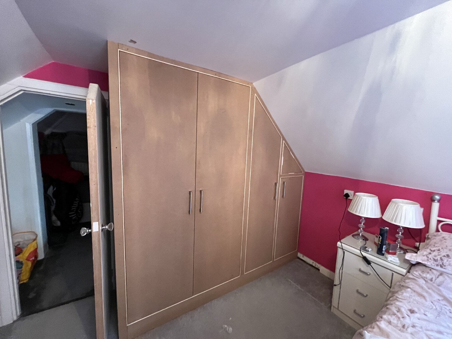 Bespoke fitted wardrobes built beneath a sloping bedroom ceiling