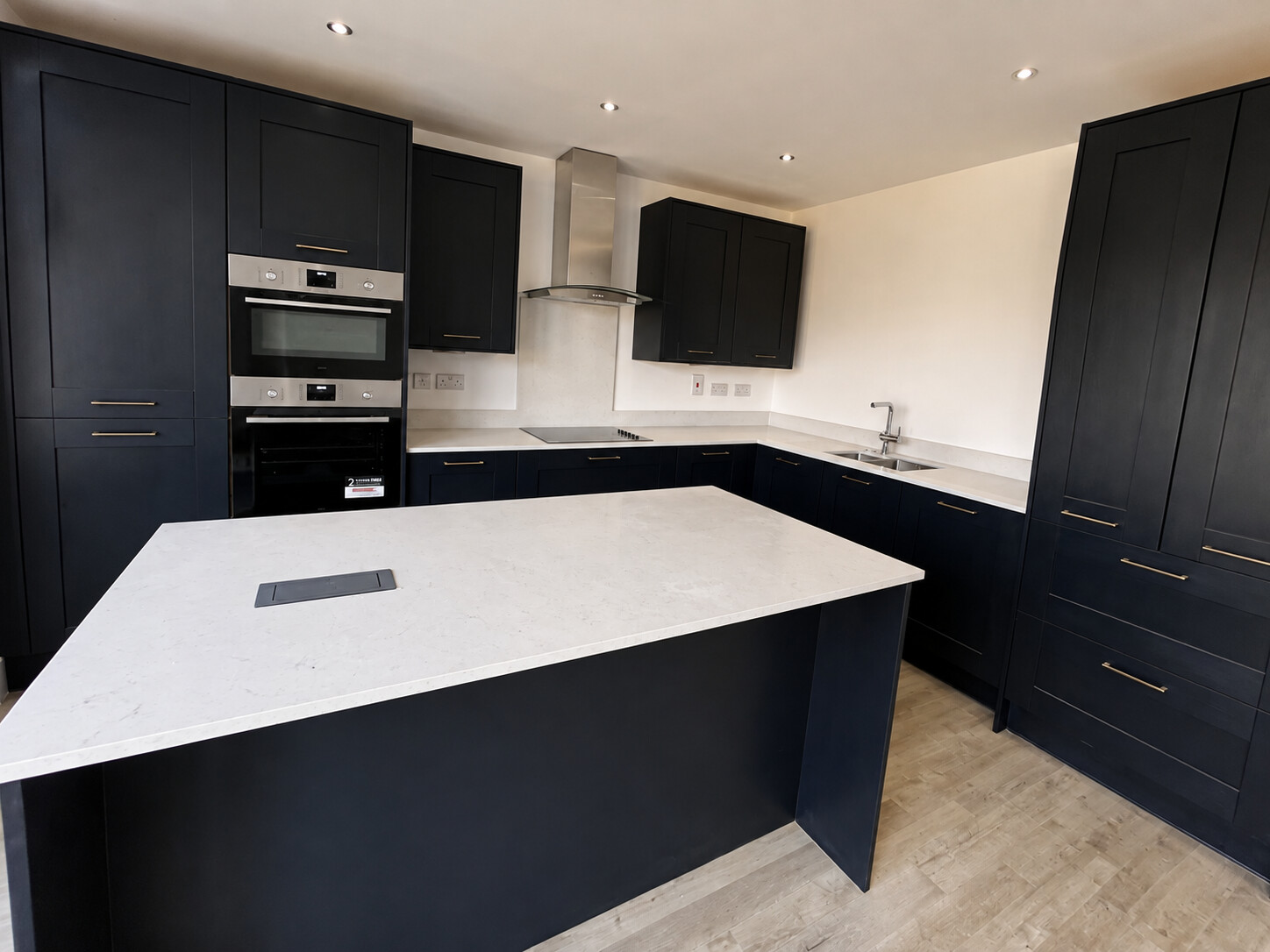 Completed dark shaker kitchen with island and aligned cabinet runs