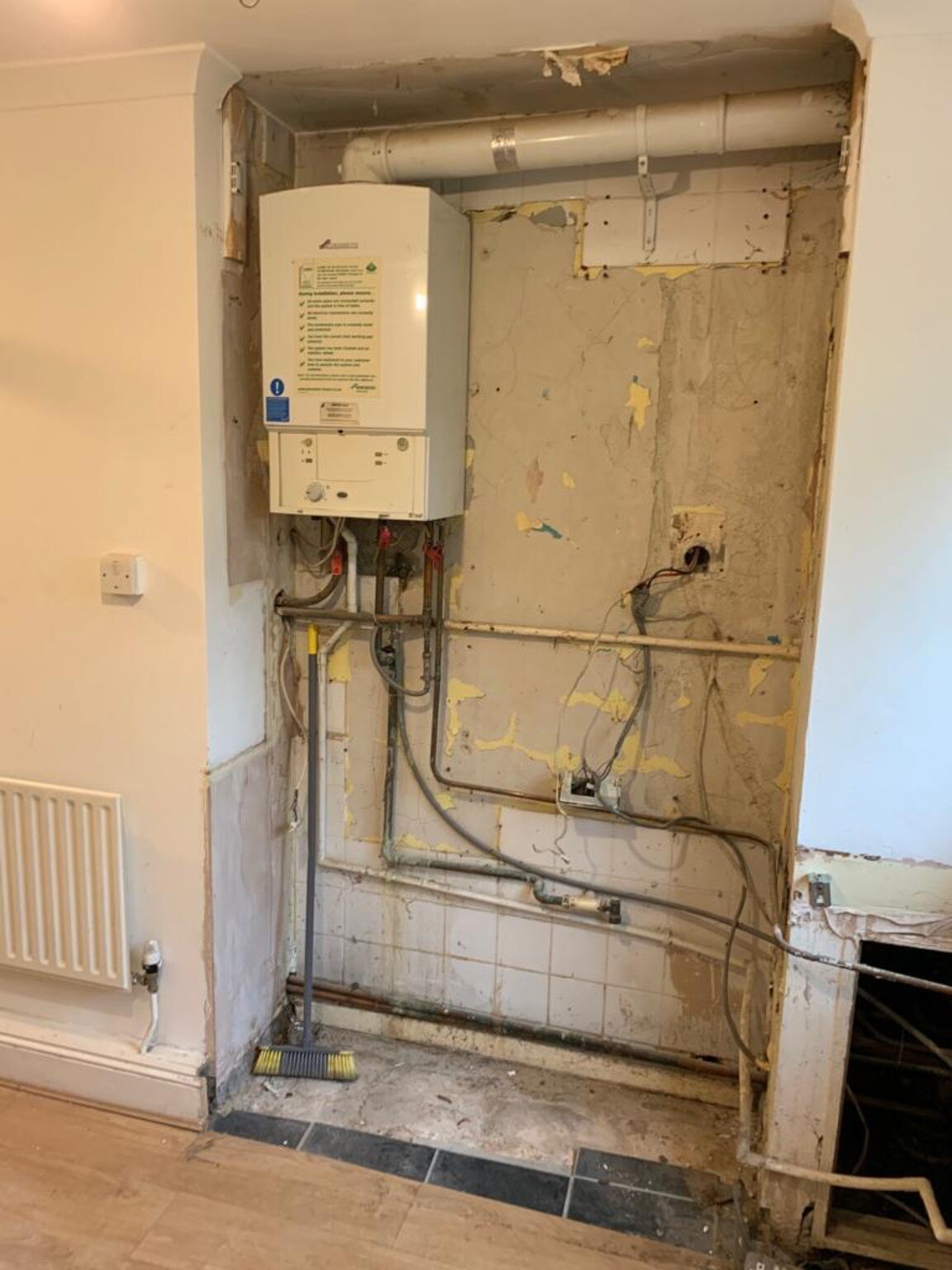 Old boiler and exposed services before relocation in a Pagham kitchen