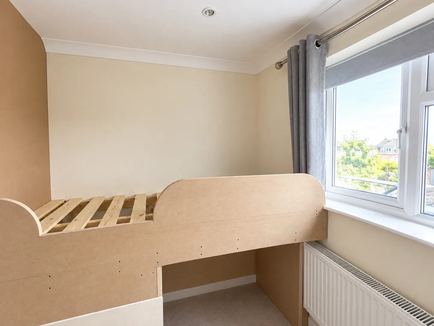 Raised MDF bed platform positioned beside the window and radiator