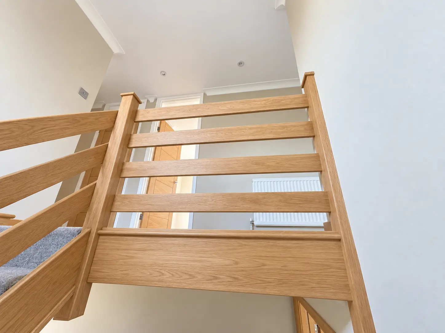 Light-oak balustrade viewed from below at the upper landing