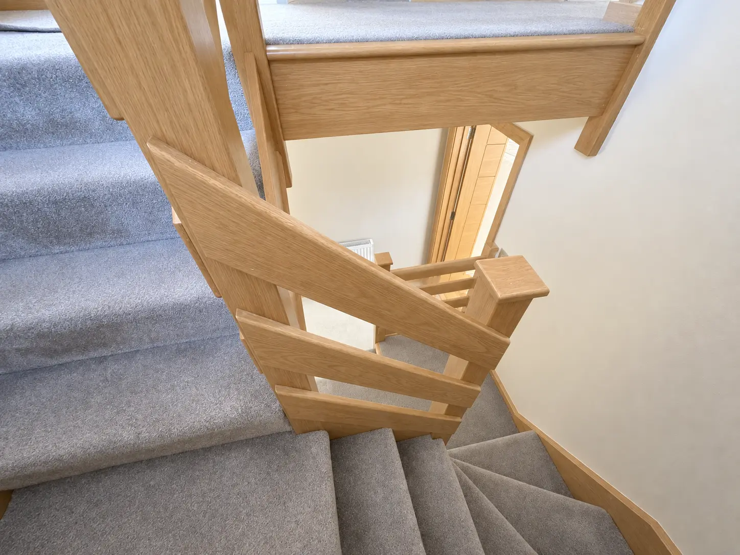 Light-oak staircase viewed down the winder flight