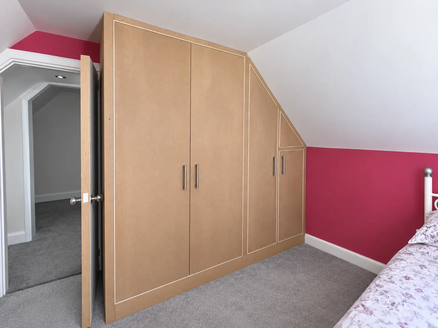 Fitted MDF wardrobe following a sloping bedroom ceiling, ready for decoration
